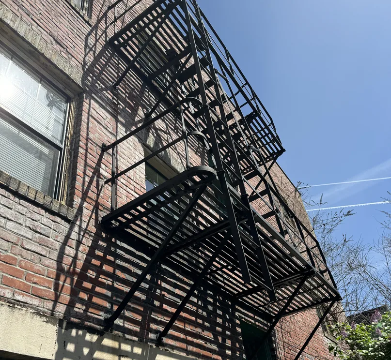 Freshly painted black iron fire escape on a Portland brick apartment building after restoration